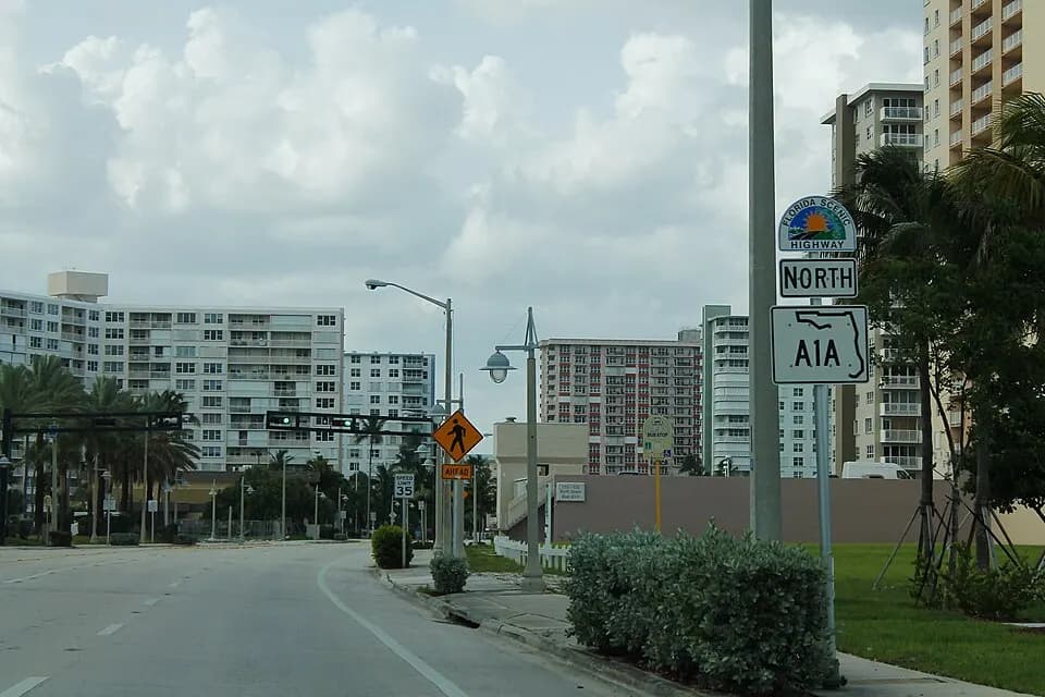 Placa da rodovia A1A com prédios de condomínio ao fundo, em Pompano Beach